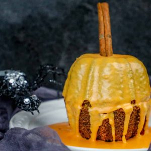 A moist spiced pumpkin bread bundt cake recipe decorated with icing and a spider for halloween.