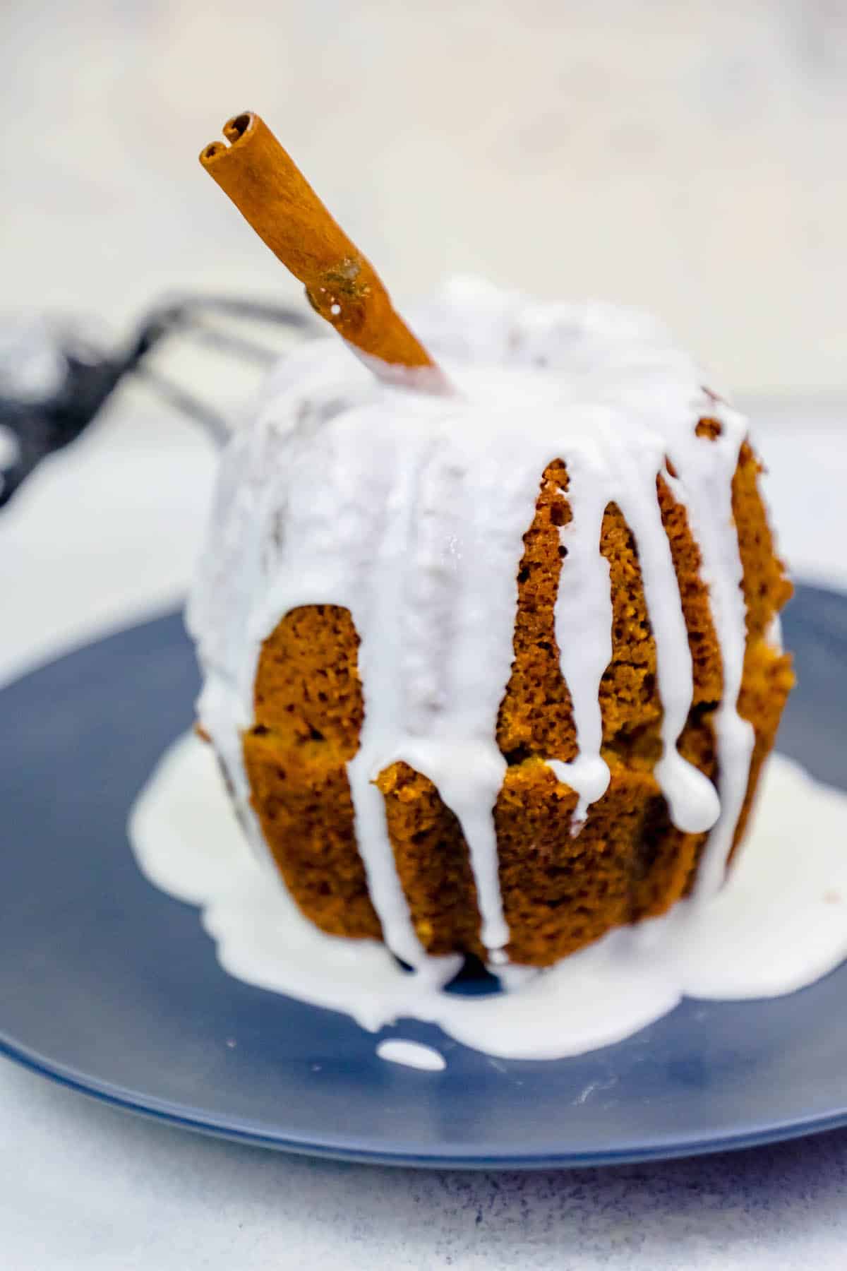 pumpkin Bundt cake together with cinnamon stick in it and white glaze