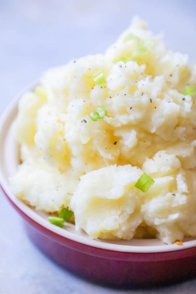 mashed potatoes with green onions in a white bowl