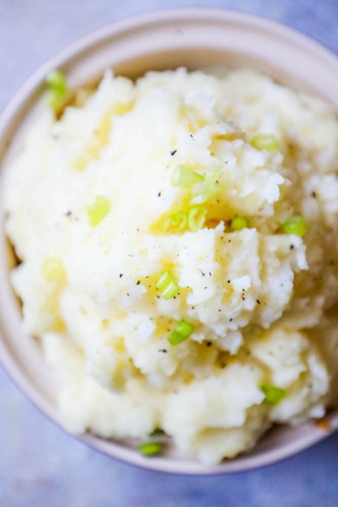 mashed potatoes with green onions in a white bowl