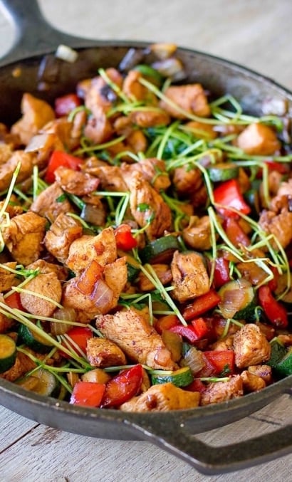 skillet with chicken, bell pepper, zucchini, and sprouts