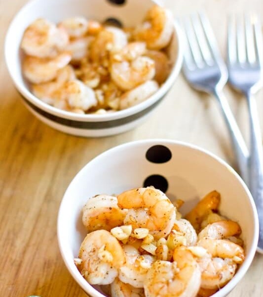 Two bowls of salt and pepper shrimp on a wooden table.