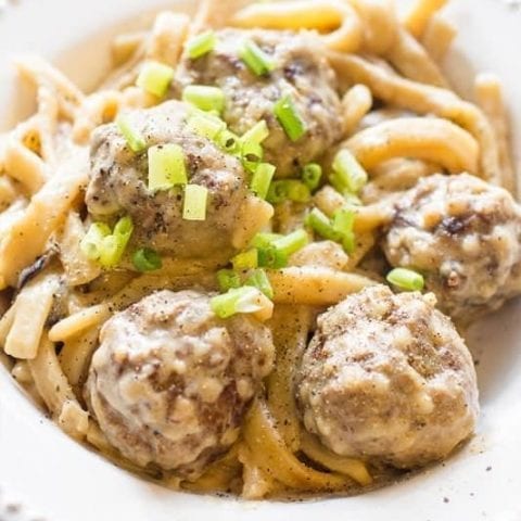 Swedish porcupine meatballs served in a white bowl with green onions.