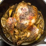 A whole roasted Greek chicken cooked in a cast iron Dutch oven with lemon, oregano, and butter.