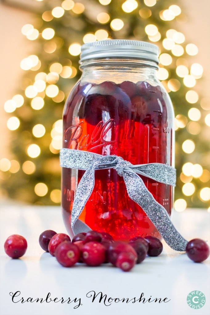 mason jar full of cranberry moonshine with cranberries in it. Lights in the background. 