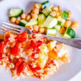 A plate with rice, tomatoes and chickpeas, topped with easy baked fish.