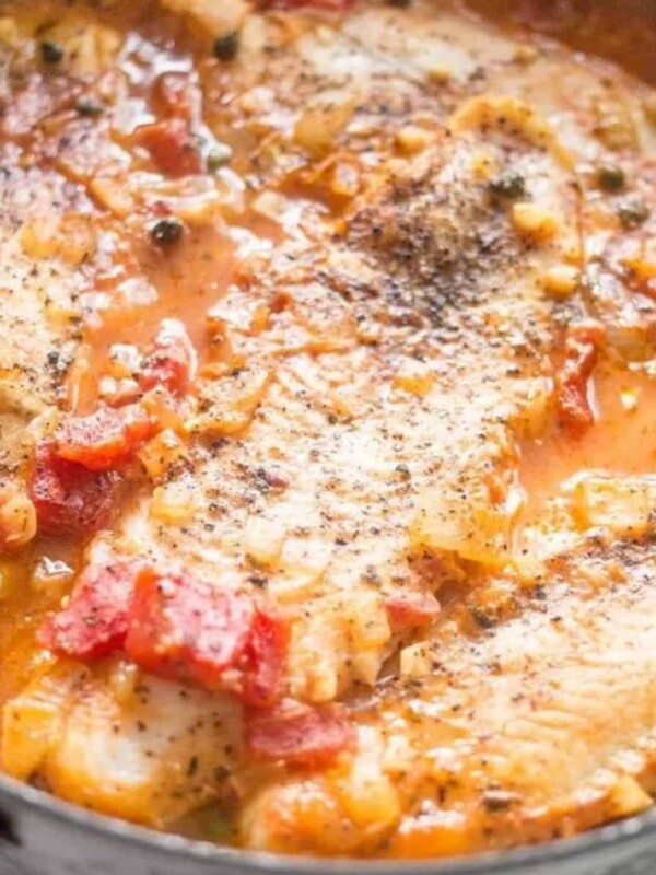 Fish fillets in a Tuscan tomato sauce cooked in a skillet.