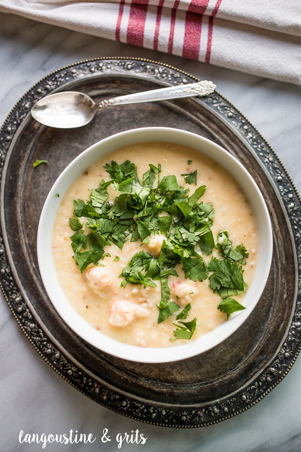 creamy grits with chunks of langoustine in a white bowl topped with parsley