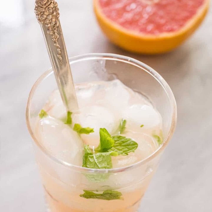 A refreshing cocktail featuring grapefruit and mint, served in a glass with a hint of pink gin.