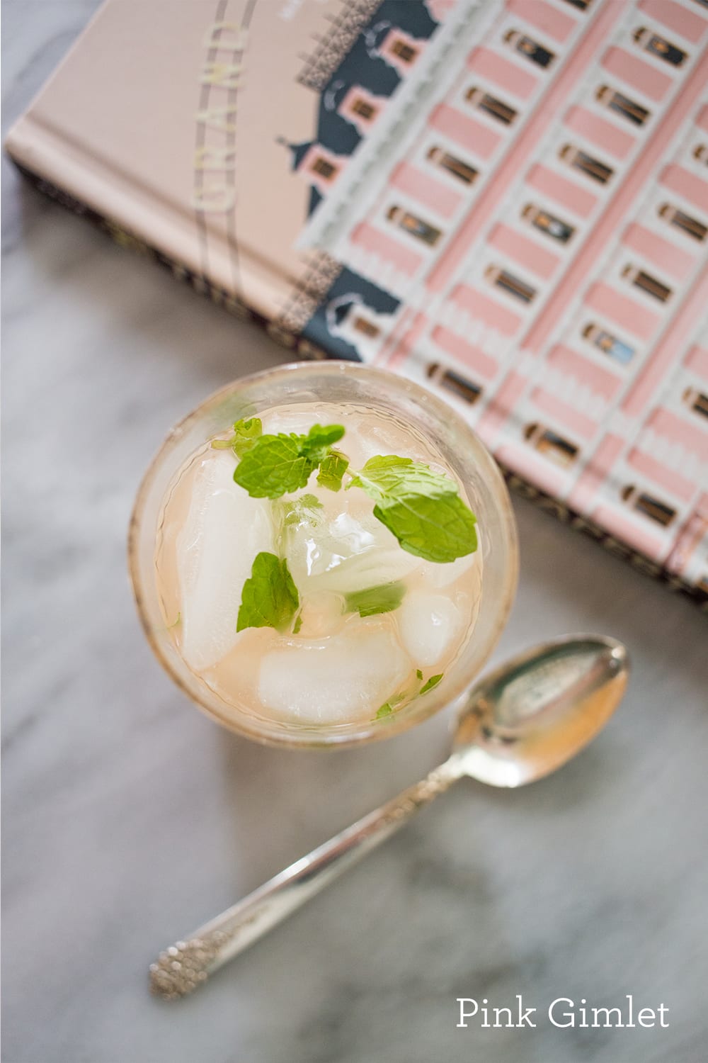 drink with mint and ice in a cup and a pink book in the background