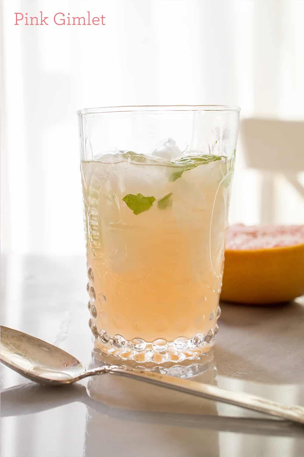 drink with mint and ice in a cup and grapefruit in the background