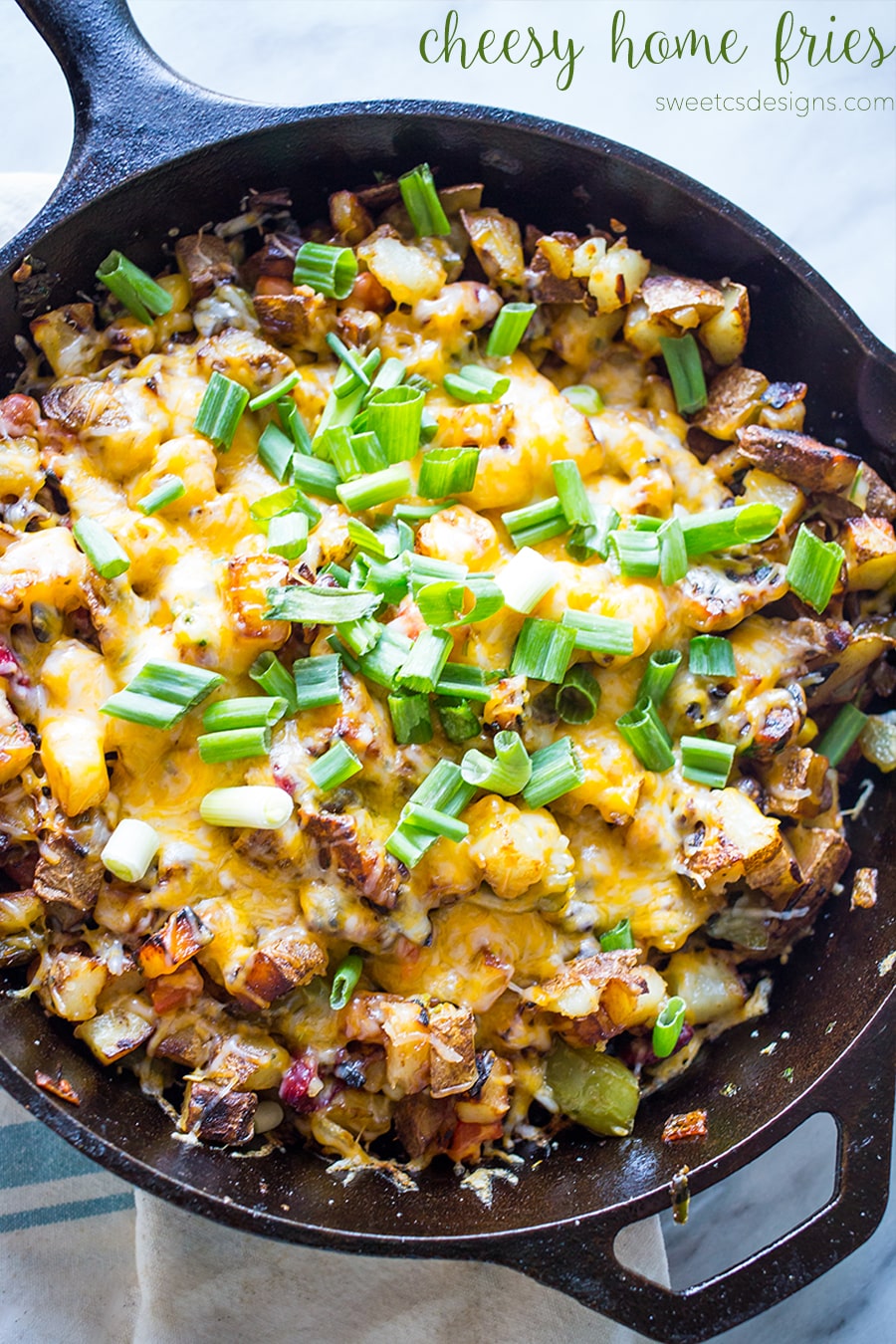 potatoes, zucchini, cheese, and green onions in a cast iron skillet