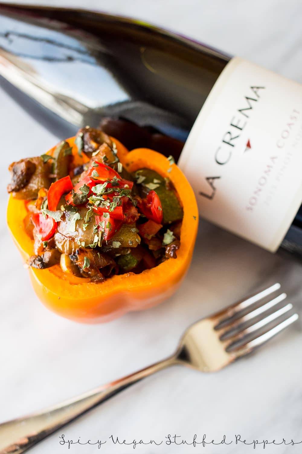 bell pepper with sauteed vegetables in it and wine in the background