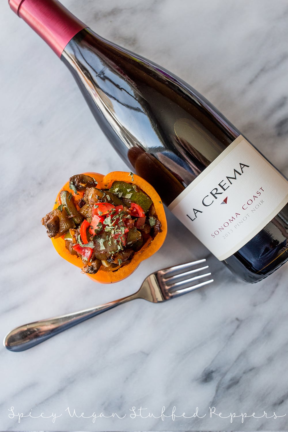 bell pepper with sauteed vegetables in it and wine in the background