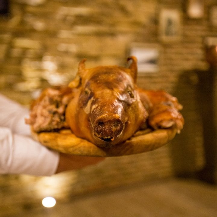 During a Georgian Supra, a man proudly balances a pig on a wooden plate.