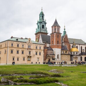 A grand castle overlooks a sprawling green field in Krakow.