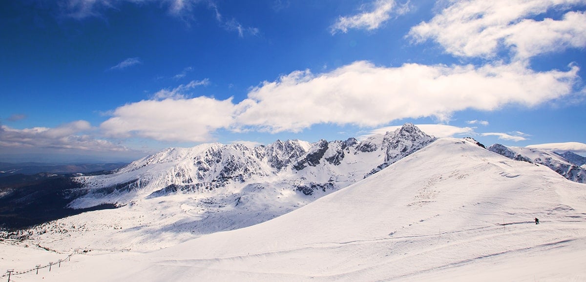 mountains covered in snow with someone skiing on one of them