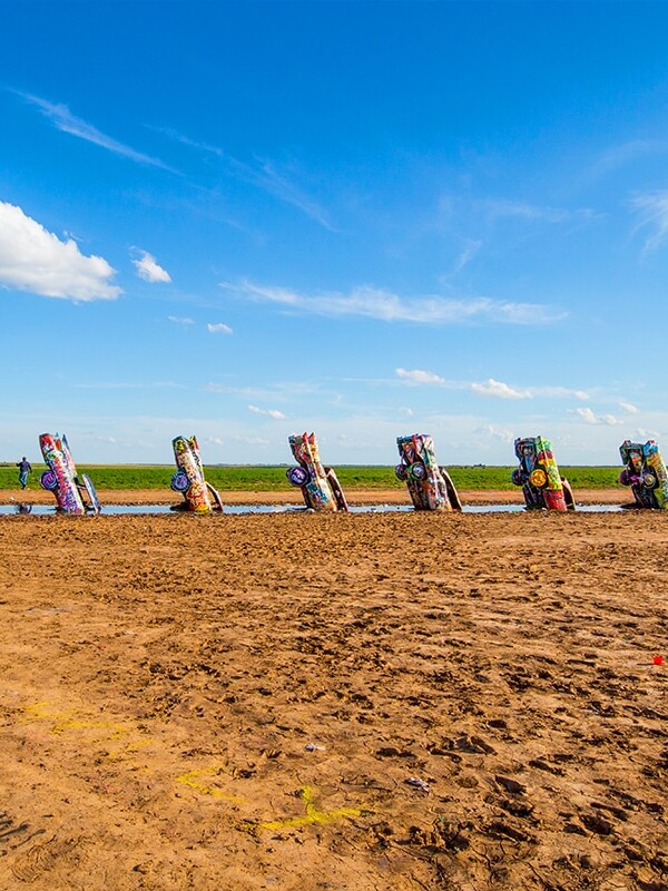 A field of wooden sculptures resembling the iconic Cadillac Ranch located in Amarillo, Texas.