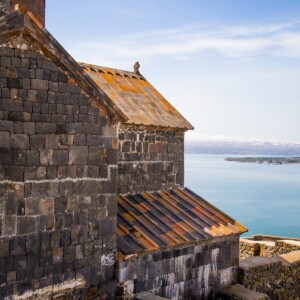 A stone building and Sevanavank Monastery Ruins against the backdrop of a blue sky over Lake Sevan in Armenia.