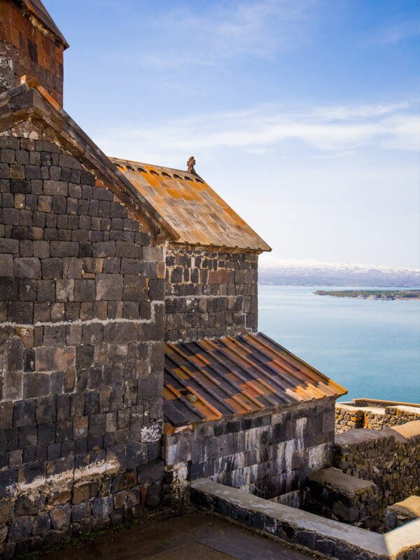 A stone building and Sevanavank Monastery Ruins against the backdrop of a blue sky over Lake Sevan in Armenia.