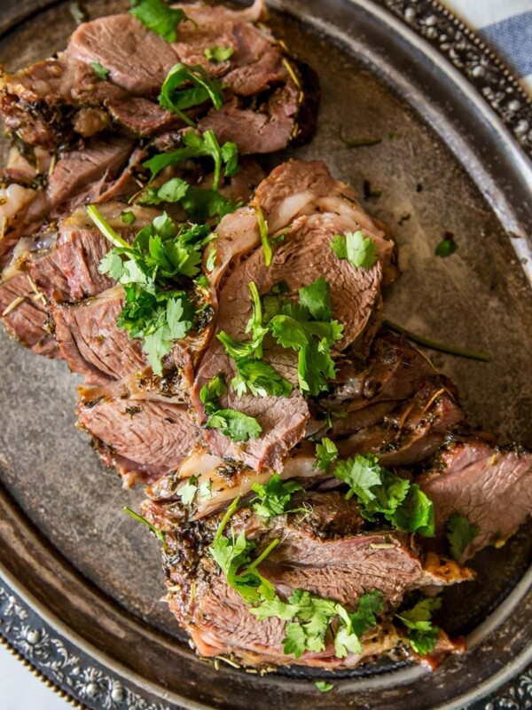 The best roasted leg of lamb served on a silver platter with herbs, perfect for Easter.