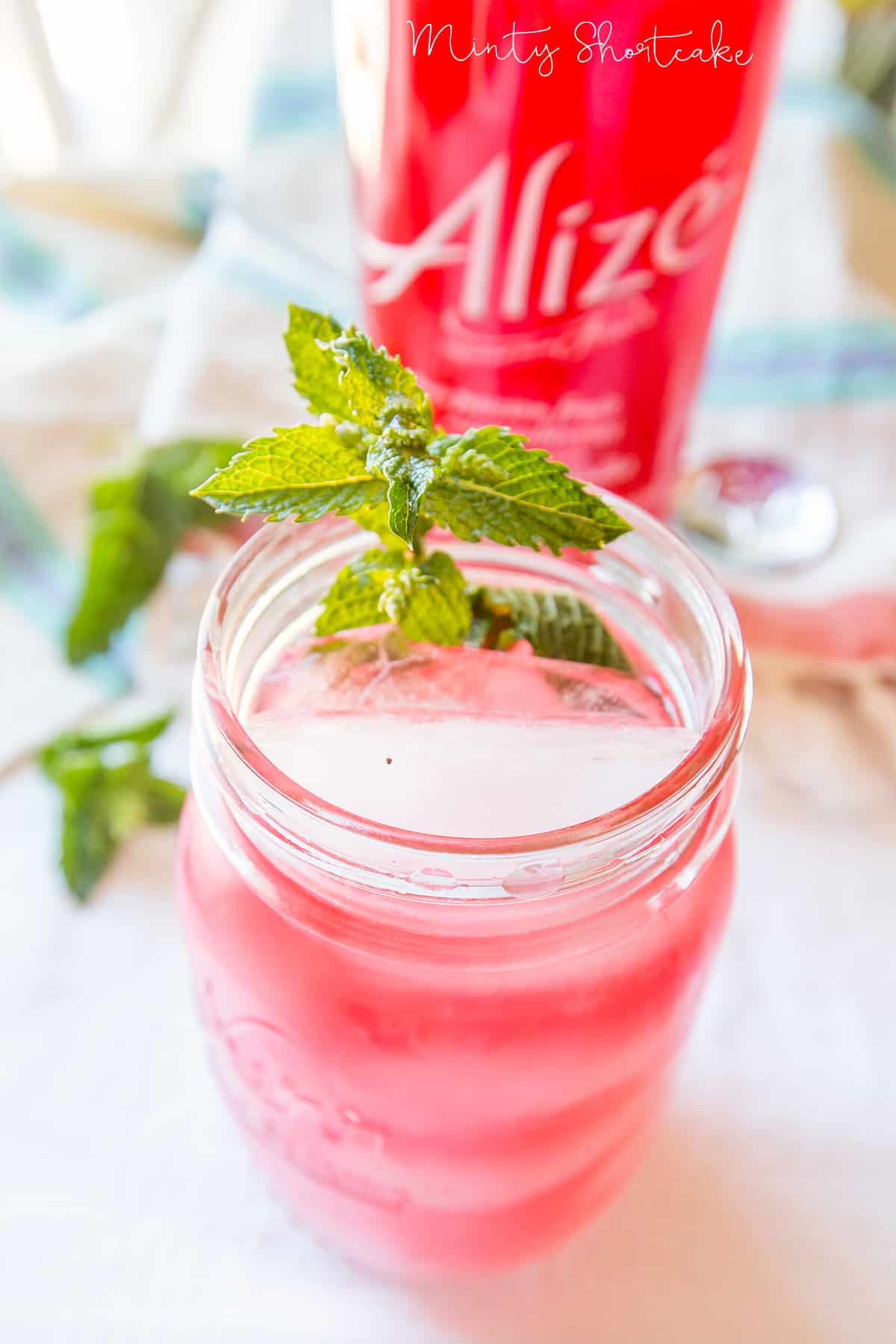 jar with pink cocktail, lemon, and mint in it 