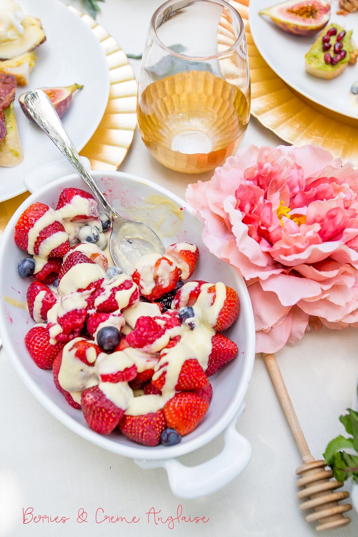 strawberries, blueberries, and raspberries in a bowl with cream and a spoon