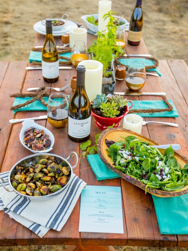 A fall harvest table scape adorned with a bounty of food and succulent centerpieces.