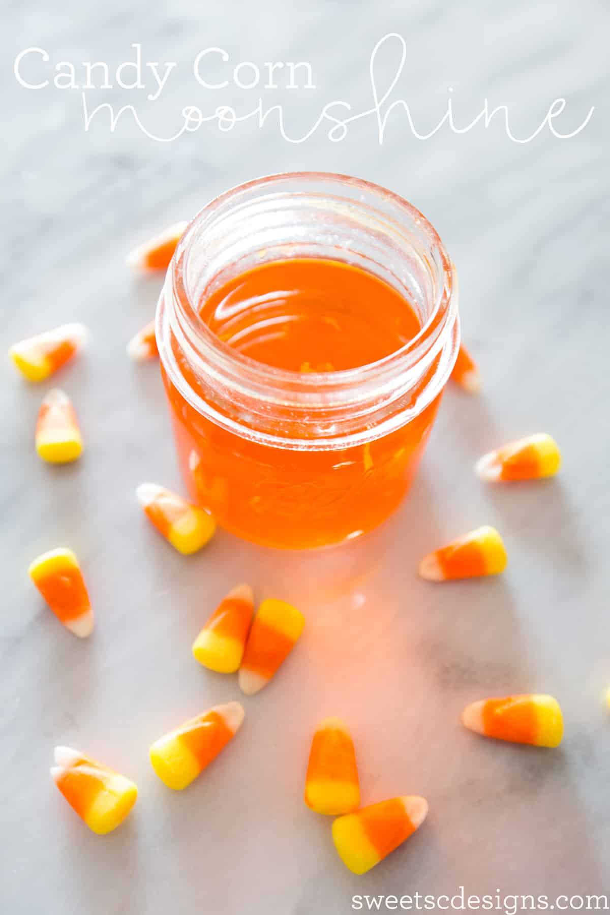 orange moonshine in a jar with candy corn around it