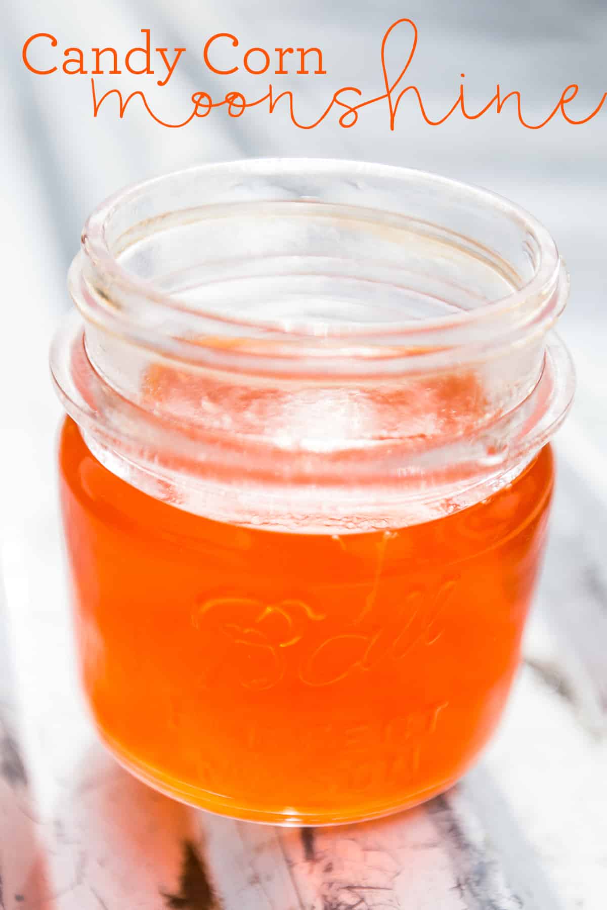 orange moonshine in a jar with candy corn around it