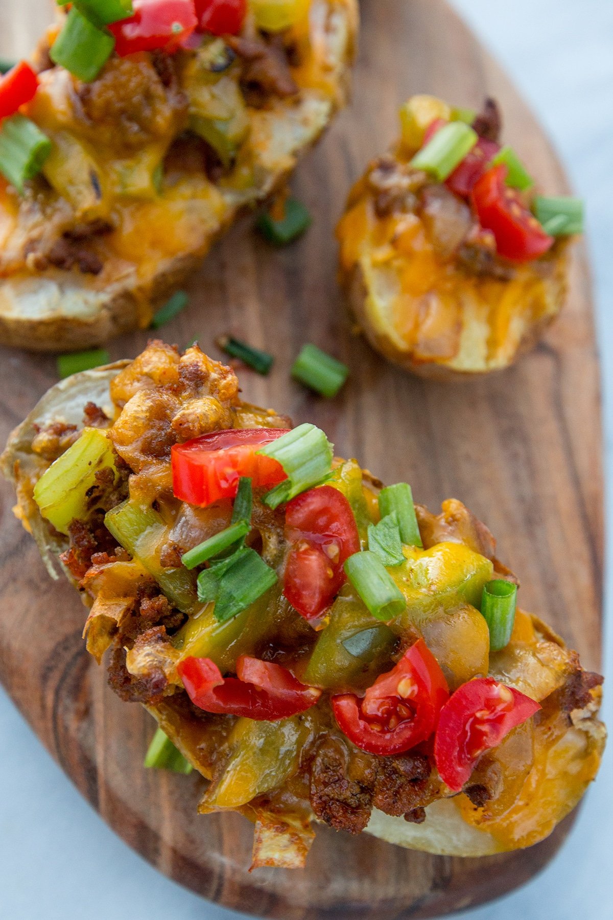 Potatoes hallowed out with taco filling in them and cheese melted on top with green onions on them. 