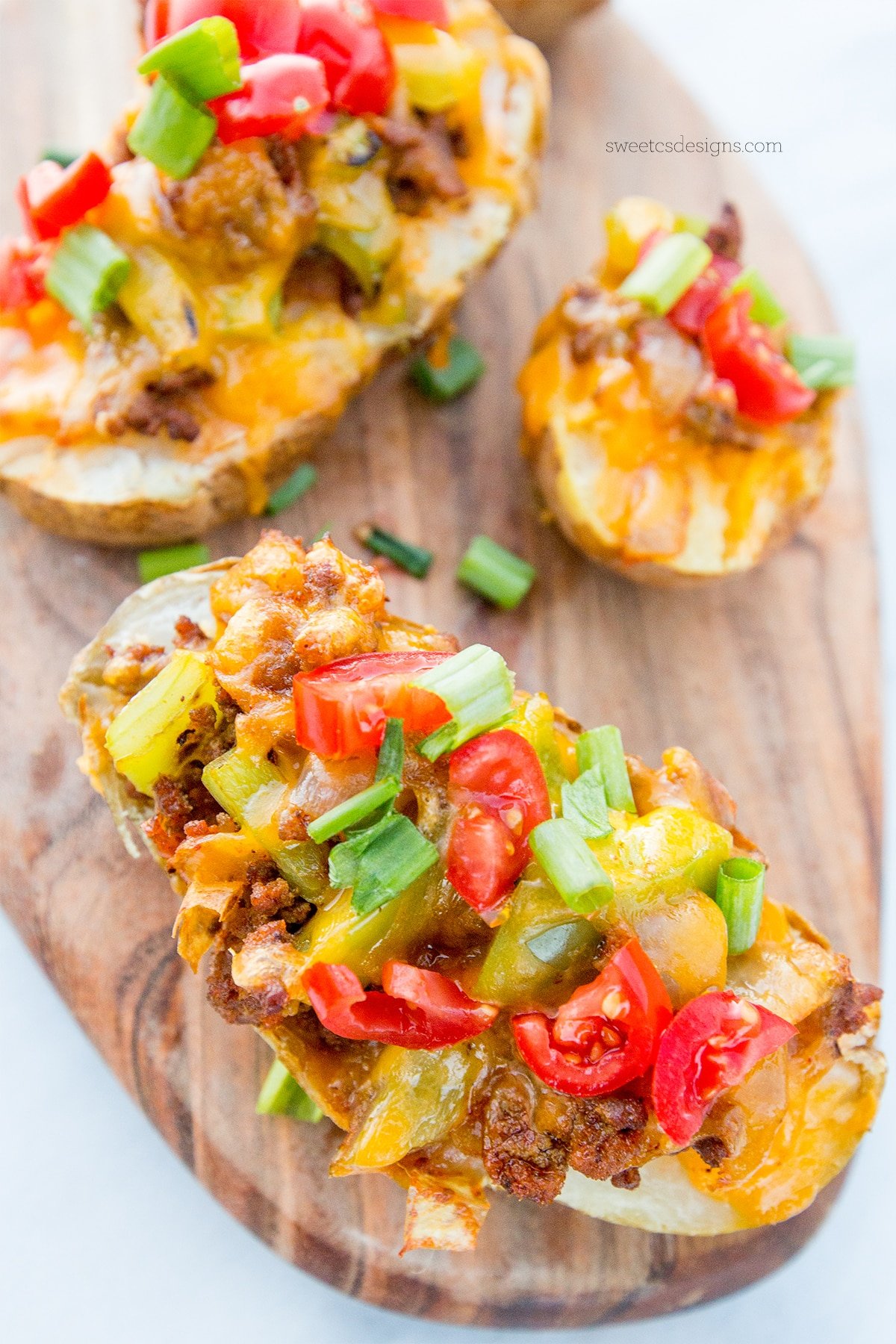 Potatoes hallowed out with taco filling in them and cheese melted on top with green onions on them. 