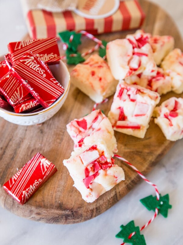 Peppermint bark adorned with candy canes and Andes candies on a cutting board.