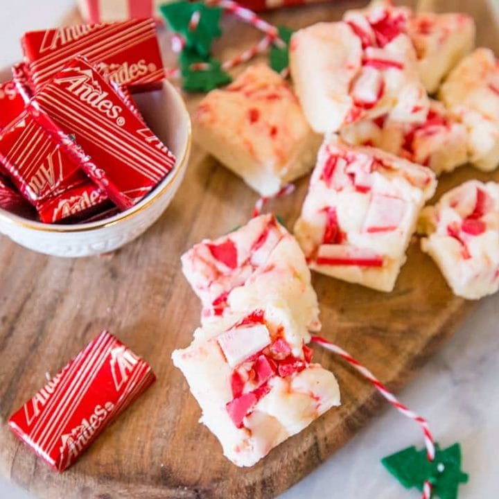 Peppermint bark with candy canes and fudge on a cutting board.