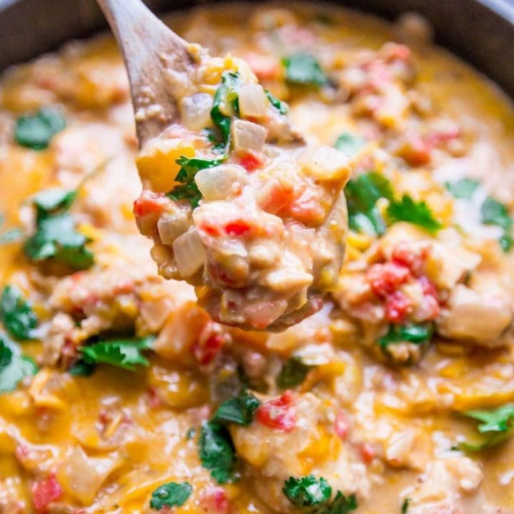 Cheesy and flavorful chicken enchilada soup cooked in one pot pan with a spoon.
