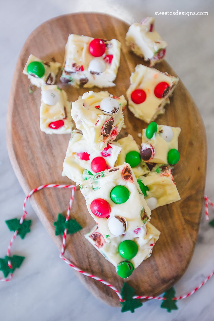Cookie dough fudge with Christmas candy on a wooden cutting board stacked