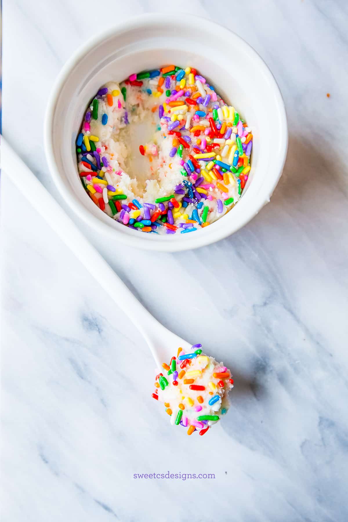 white fudge with sprinkles in a bowl with a spoon