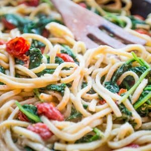 Spinach and tomatoes cooked with pasta in a skillet.