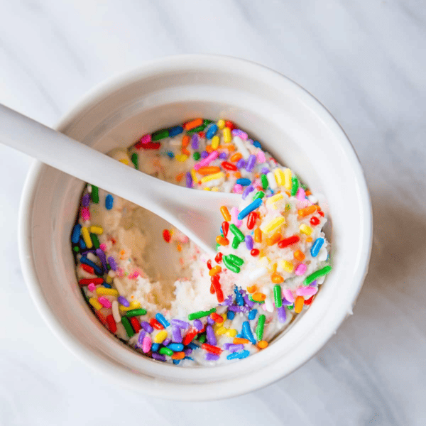 A bowl of cake batter ice cream with fudge sprinkles.