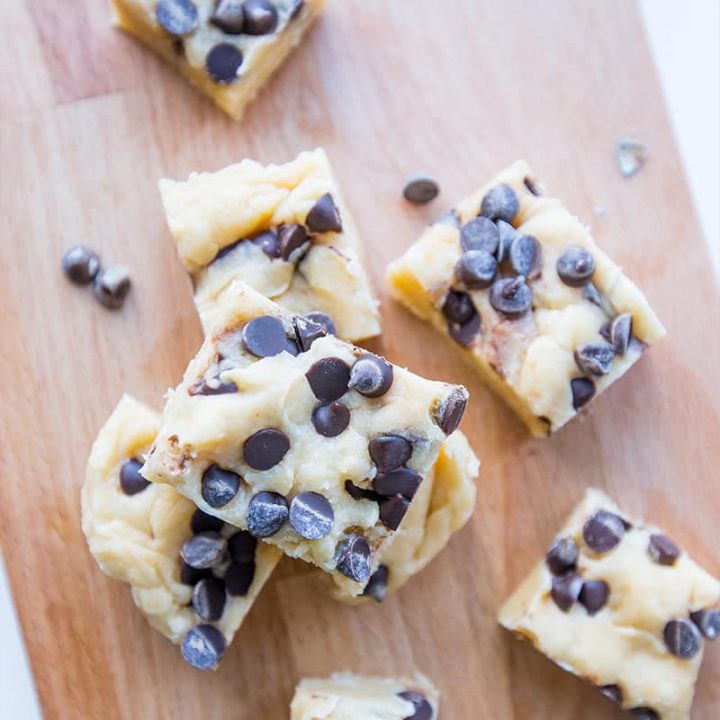 Chocolate chip cookie dough bars with fudge on a cutting board.