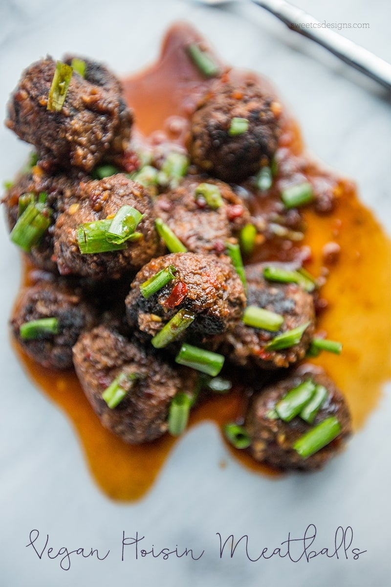 meatballs in a pile with rich Asian sauce on top and green onions