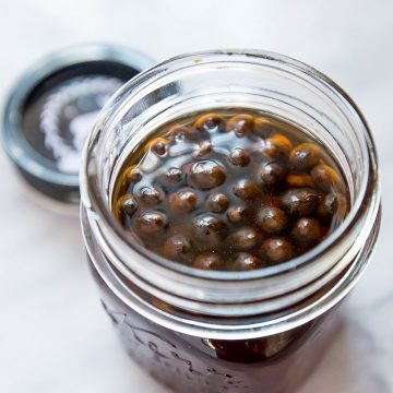 coffee beans in vodka in a mason jar with lid off
