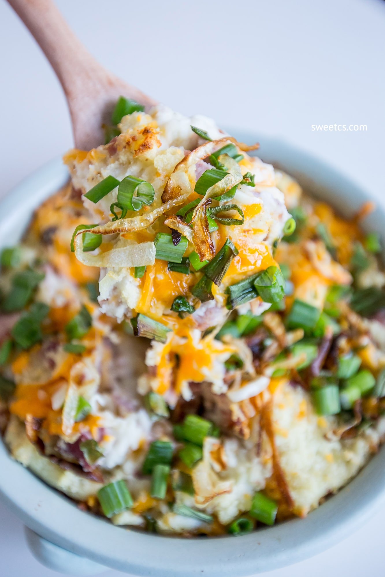 mashed potatoes, cheese, ham, and green onions in a dish