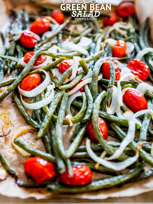 Roasted green beans and tomatoes on a baking sheet for a refreshing salad.