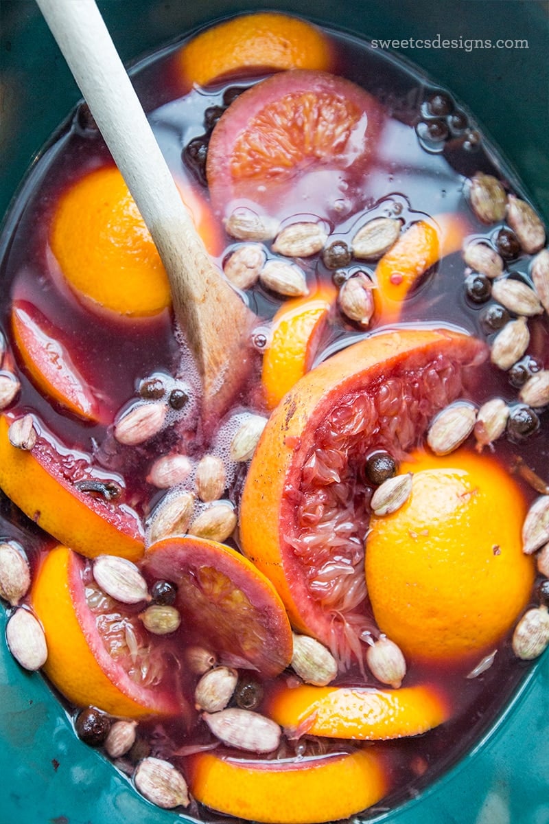 crock pot with sliced oranges, peppercorns, and cardamon and juice