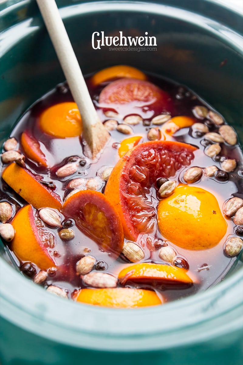 crock pot with sliced oranges, peppercorns, and cardamon and juice