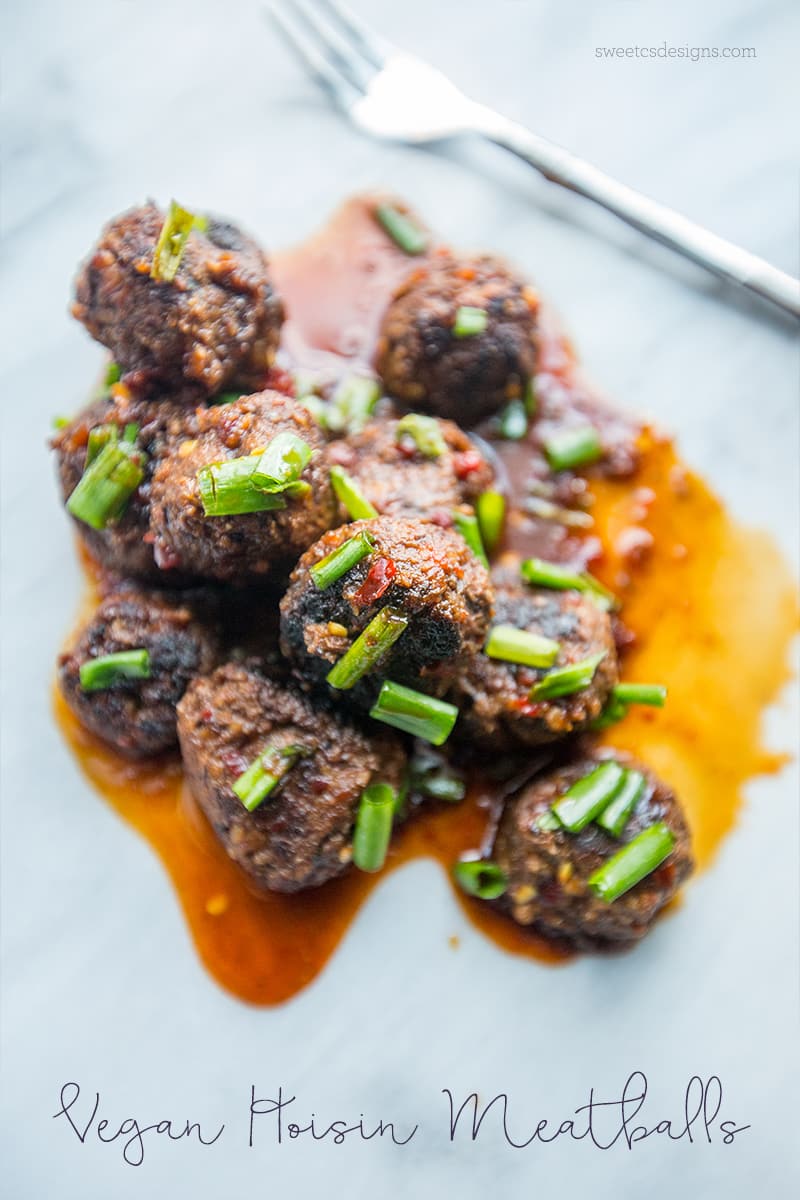 meatballs in a pile with rich Asian sauce on top and green onions