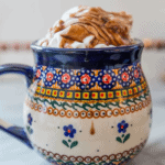 A decorative ceramic mug filled with ice cream, drizzled with chocolate espresso syrup.