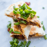 A stack of meaty vegan quesadillas with green onions.