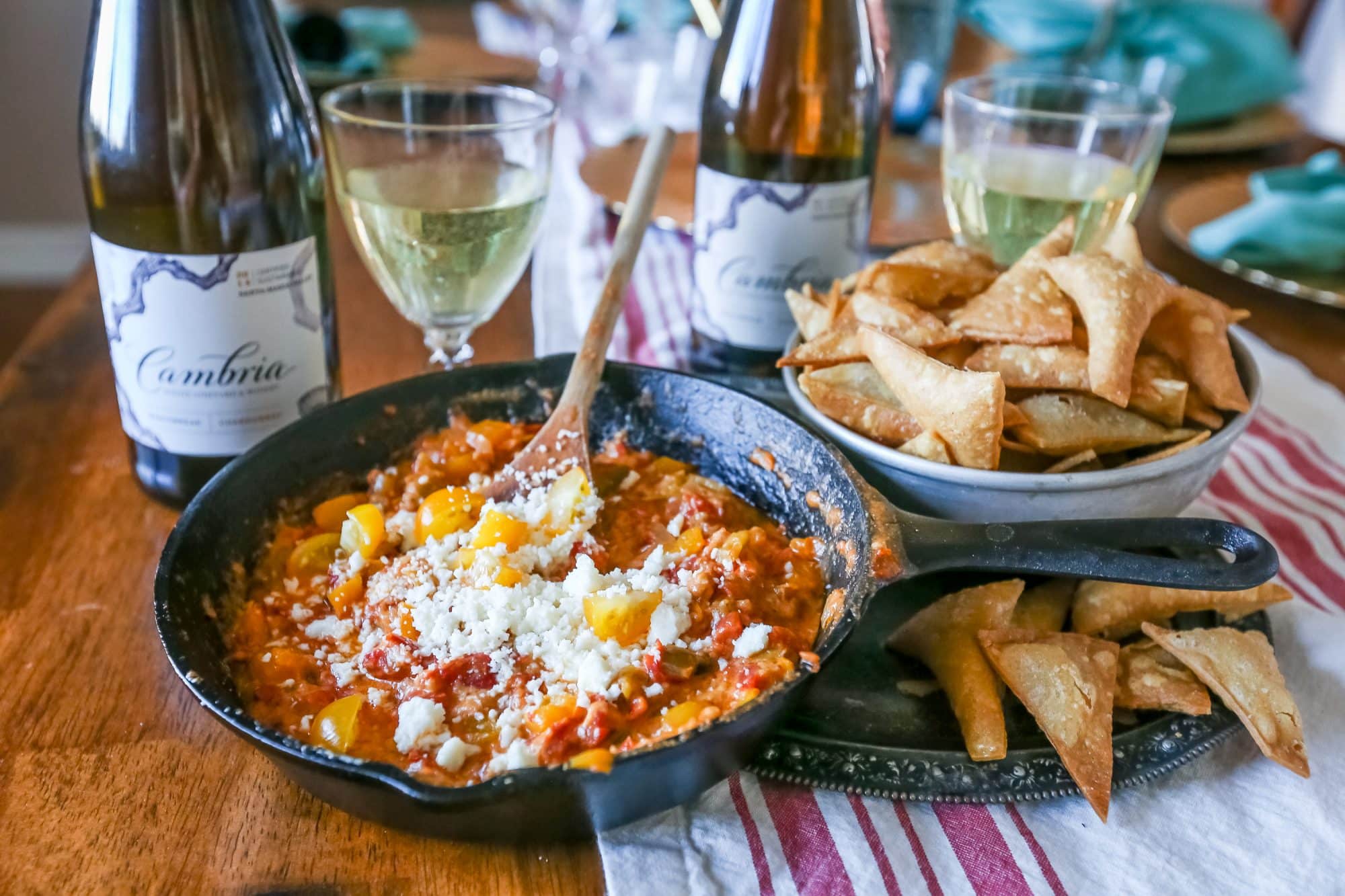 green chili, pepper, cheesy skillet with cheese on it, homemade chips in background and cambria wine.